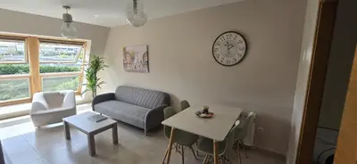 a living room with a couch and a table and a clock at Ático Paraíso in San Ciprián