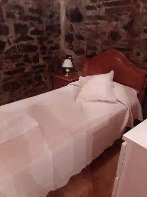 a bedroom with a white bed and a stone wall at Medulillas in Yeres