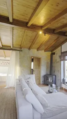 a large white couch in a room with a fireplace at Casiña Raíz Entre viñas y cielo Ribeira Sacra in Chantada