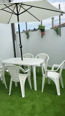 a white table and chairs with an umbrella at Piso con terraza y garaje a un Paso de la Playa de Tapia in Tapia de Casariego
