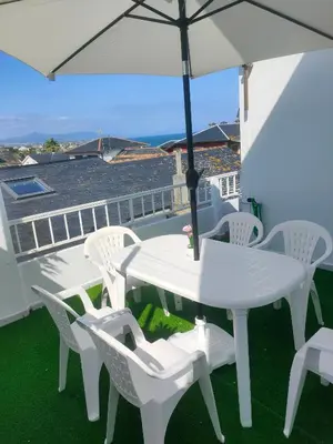 a white table and chairs on a balcony with an umbrella at Piso con terraza y garaje a un Paso de la Playa de Tapia in Tapia de Casariego