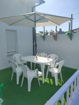 a white table and chairs with an umbrella on a balcony at Piso con terraza y garaje a un Paso de la Playa de Tapia in Tapia de Casariego