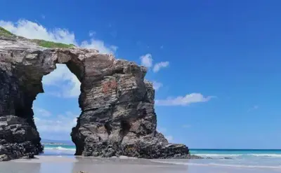 an arch in a rock formation on the beach at EnFOZ 1ª Línea de Playa II in Foz