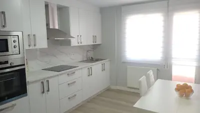 a kitchen with white cabinets and a table with a bowl of fruit at Luz de Guía in Burela de Cabo