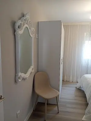 a bedroom with a chair and a mirror on the wall at Luz de Guía in Burela de Cabo