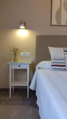 a bedroom with a white bed and a nightstand with a white bed sidx sidx at Vivienda de Uso Turístico Los Castaños in San Román de Sanabria