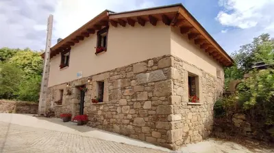 a stone building with flowers in front of it at Vivienda de Uso Turístico Los Castaños in San Román de Sanabria