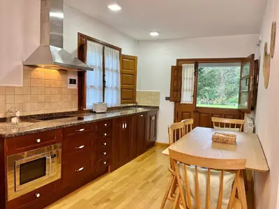 a kitchen with wooden cabinets and a wooden table with a wooden tableablish at Fuentes del Narcea apartamentos rurales in Cangas del Narcea