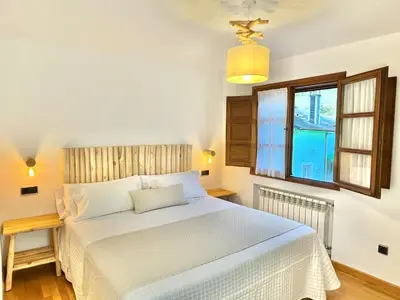 a bedroom with a white bed and a window at Fuentes del Narcea apartamentos rurales in Cangas del Narcea