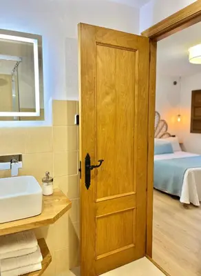a bathroom with a wooden door and a sink at Fuentes del Narcea apartamentos rurales in Cangas del Narcea