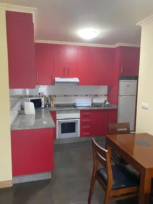 a kitchen with red cabinets and a wooden table at Terra 1B in Caldas de Reis