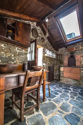 a stone room with a wooden table and chairs at Villa rural en Playa de Frejulfe in Frejulfe