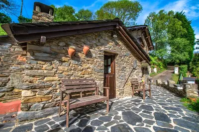 a wooden bench sitting outside of a stone building at Villa rural en Playa de Frejulfe in Frejulfe
