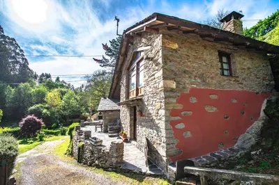 a stone house with a red door on the side of it at Villa rural en Playa de Frejulfe in Frejulfe