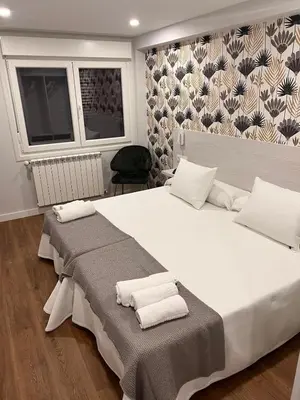 a bedroom with a large white bed with towels on it at Sleep Padrón in Padrón