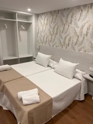 a bedroom with two beds with white pillows at Sleep Padrón in Padrón