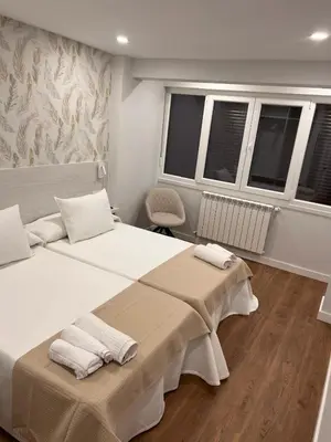 a bedroom with two beds and two windows at Sleep Padrón in Padrón