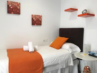a bedroom with an orange and white bed and a table at Pensión Residencia Fonseca in Santiago de Compostela