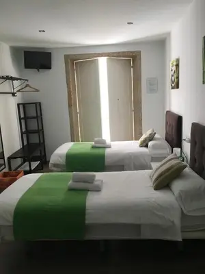 a room with three beds with green and white sheets at Pensión Residencia Fonseca in Santiago de Compostela