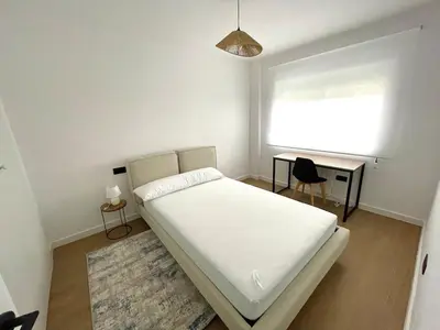 a bedroom with a bed and a desk and a window at Cozy and centrally located apartment in Santiago de Compostela
