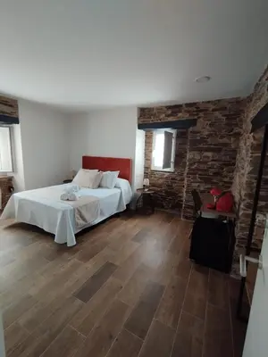a bedroom with a bed and a brick wall at Pension Silvent in Ribadeo