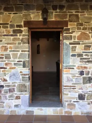 an open doorway into a stone building with a brick wall at El Mirador de los Trobos in Villar de Otero