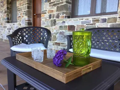 a table with a green vase and flowers on it at El Mirador de los Trobos in Villar de Otero