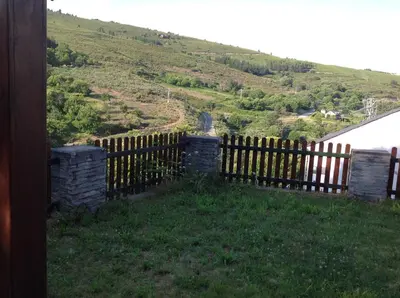 a wooden fence with a hill in the background at El Mirador de los Trobos in Villar de Otero