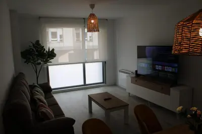 a living room with a couch and a tv and a table at Alojamiento Doble R in Villalba
