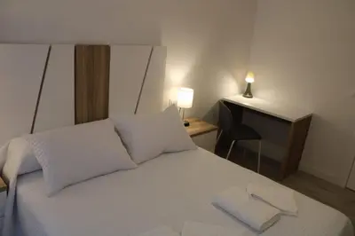 a bedroom with a white bed with two towels on it at Alojamiento Doble R in Villalba
