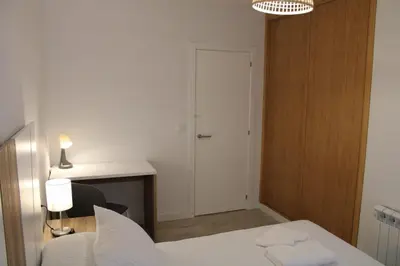 a bedroom with a bed and a desk and a door at Alojamiento Doble R in Villalba