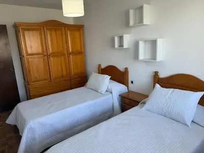 two beds in a room with white sheets at Apto Mirandés in Burela de Cabo