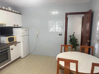a kitchen with a table and a white refrigerator at Apto Mirandés in Burela de Cabo