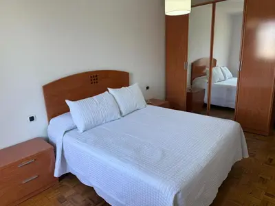 a bedroom with a white bed and a mirror at Apto Mirandés in Burela de Cabo