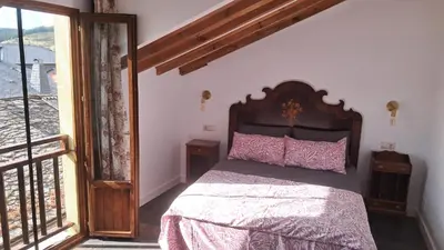 a bedroom with a bed with pink pillows and a window at Casa Loma Manolo in Molinaseca