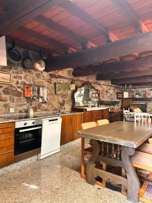 a kitchen with a wooden table and a stone wall at Casa do Cabo - 3 habitaciones con 3 baños independientes