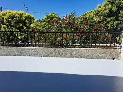 a black fence with red flowers and trees at Casa Buen Camino in Arzúa
