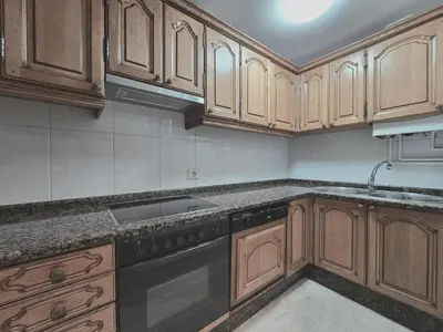 a kitchen with wooden cabinets and a black dishwasher at Apartamento Lugo centro muralla in Lugo