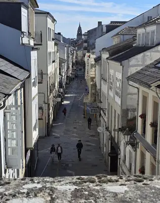 people walking down a street in a city with buildings at Apartamento Lugo centro muralla in Lugo