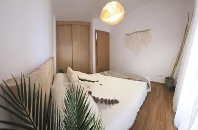 a room with a bed and a plant in it at Costa Foz Apartment Playa de Llas, terraza, piscina y pista de pádel in Foz