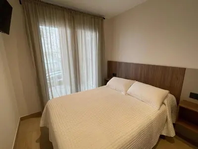 a bedroom with a bed with white sheets and a window at As Tres Praias in Burela de Cabo