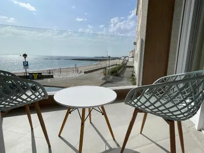two chairs and a table on a balcony with a view of the ocean at As Tres Praias in Burela de Cabo