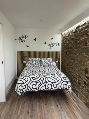 a bedroom with a bed and a stone wall at Adiva Casa Da Avoa in Puentedeume
