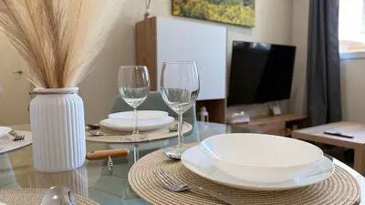 a table with two glasses and plates and a television at Carude 76 in Monforte de Lemos