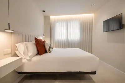 a white bedroom with a white bed and a television at Loft América 41 B in Melide