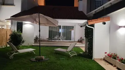 a patio with two chairs and an umbrella in the yard at Egeria Casa Jardín in Caldas de Reis