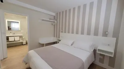 a white bedroom with a bed and a bathroom at Egeria Casa Jardín in Caldas de Reis