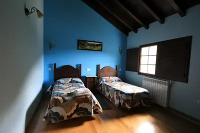 two beds in a room with blue walls at Casa Aniceto in Taramundi