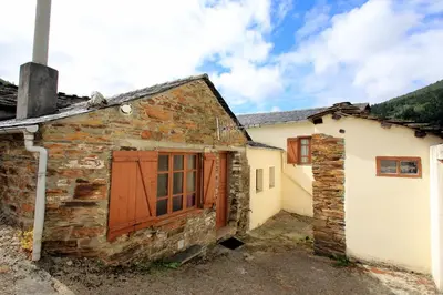 an old stone building with a red door and a garage at Casa Aniceto in Taramundi