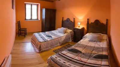 a bedroom with two beds and a table and a chair at Casa Aniceto in Taramundi